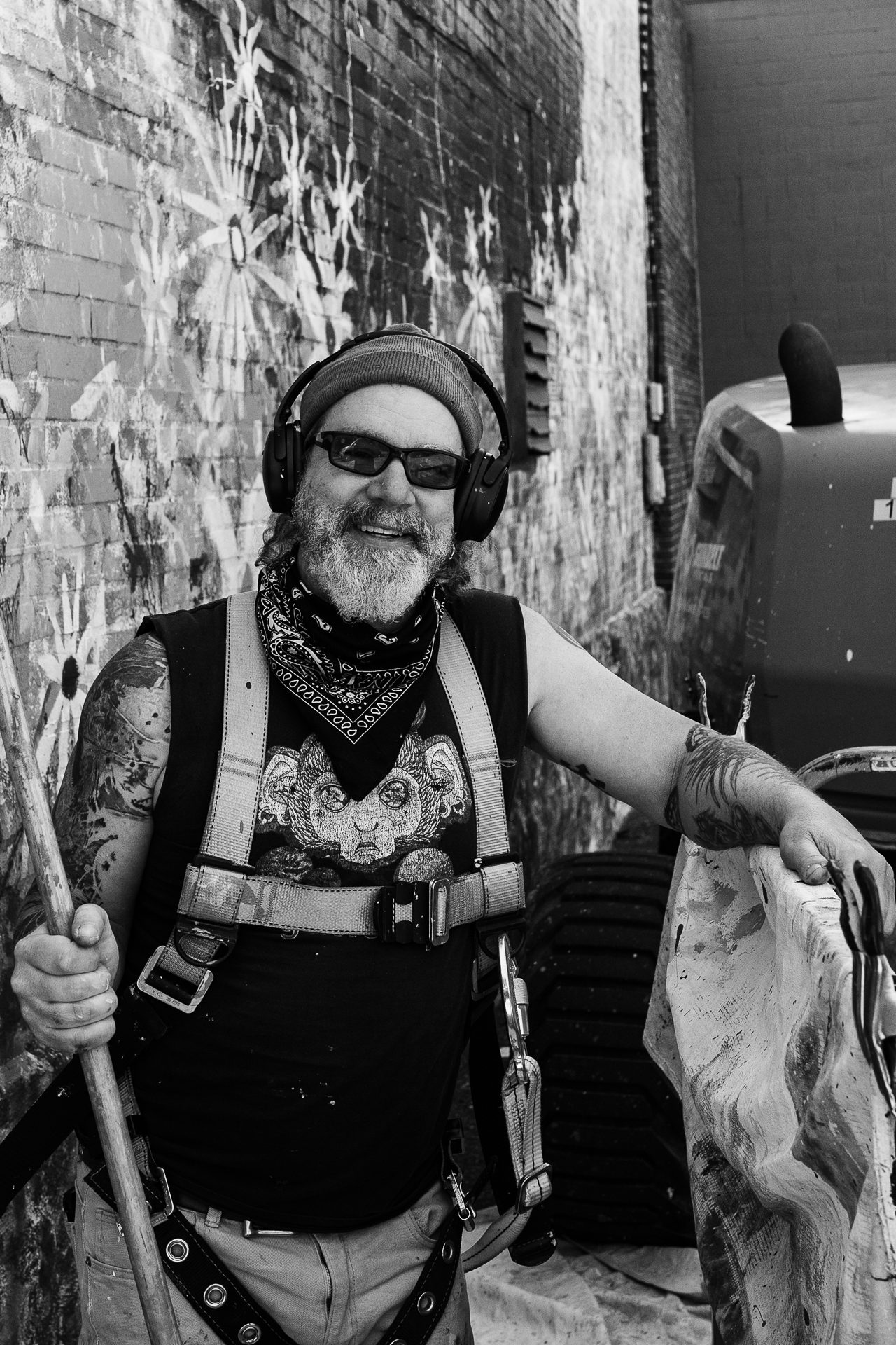 Pittsburgh Artist Scott Kowalski Posing in a boom lift in front of Love your wild neighbor mural in the strip in pittsburgh